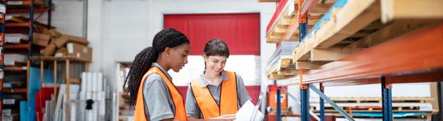 multi ethnic women workers working in a warehouse with a laptop.